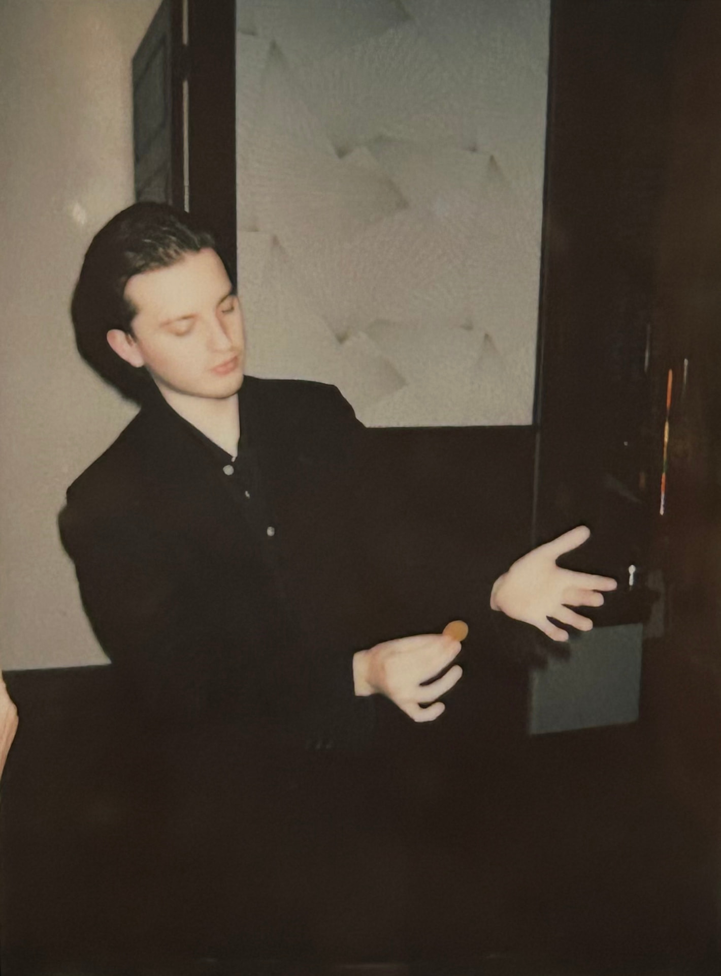 Griffin performing a coin sleight in a dark suit